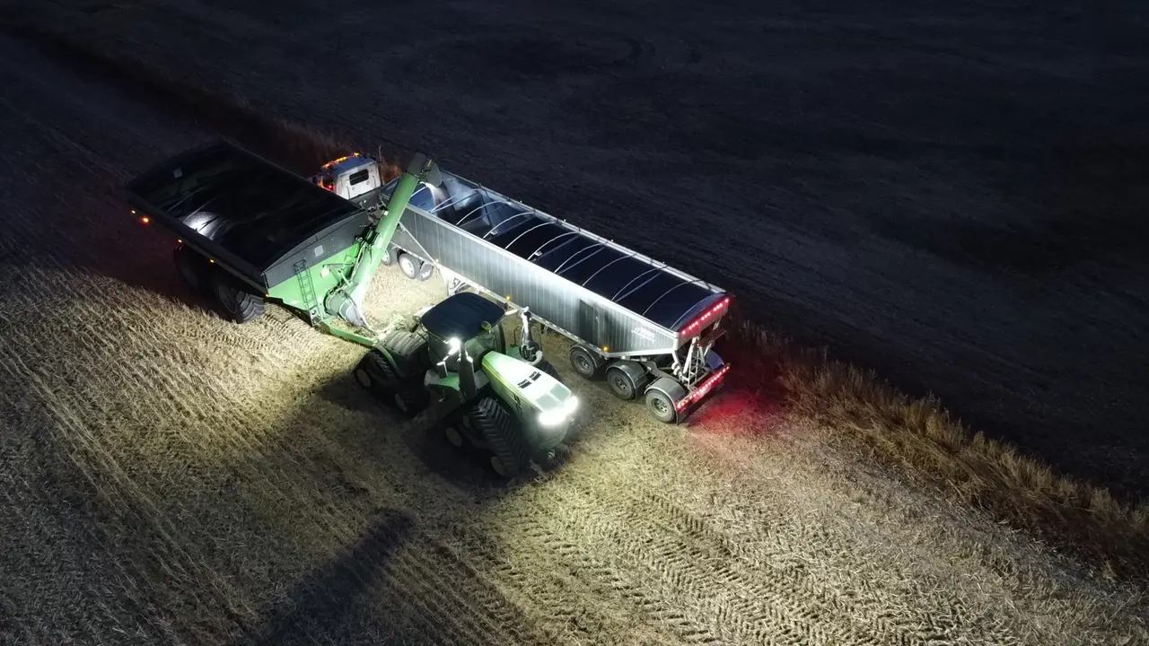 Grain cart unloading into a semi trailer at night, 2024